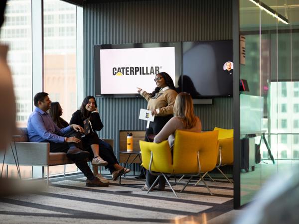 a group of people sitting in chairs and a person pointing at a screen