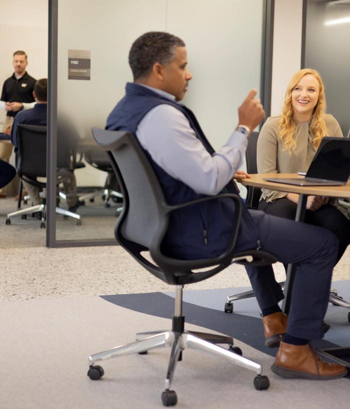 一个人和坐在一张桌子上拿着笔记本电脑的人