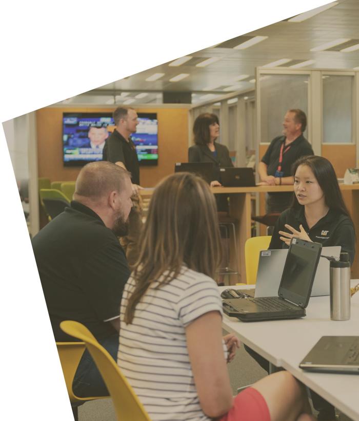 一群人围坐在一张桌子旁,桌上放着笔记本电脑