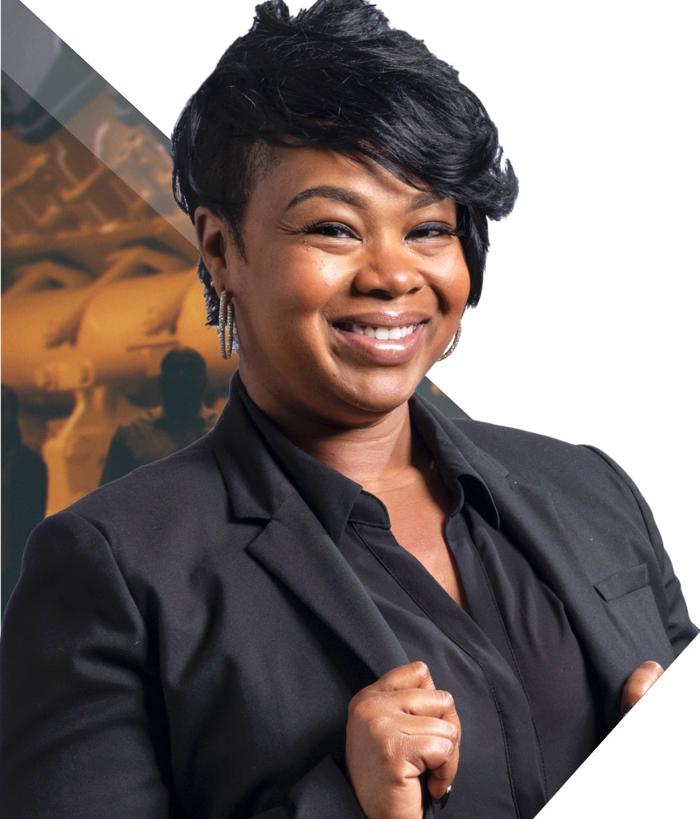 a person smiling with short hair wearing a black suit