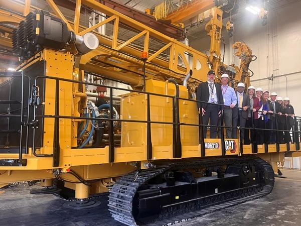 a group of people standing on a yellow machine