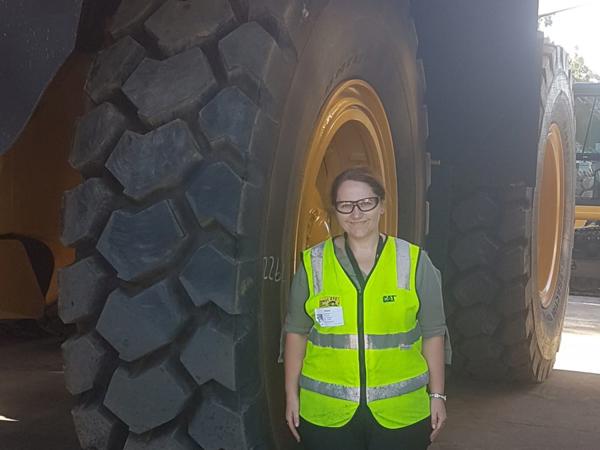 a person standing in front of a large tire